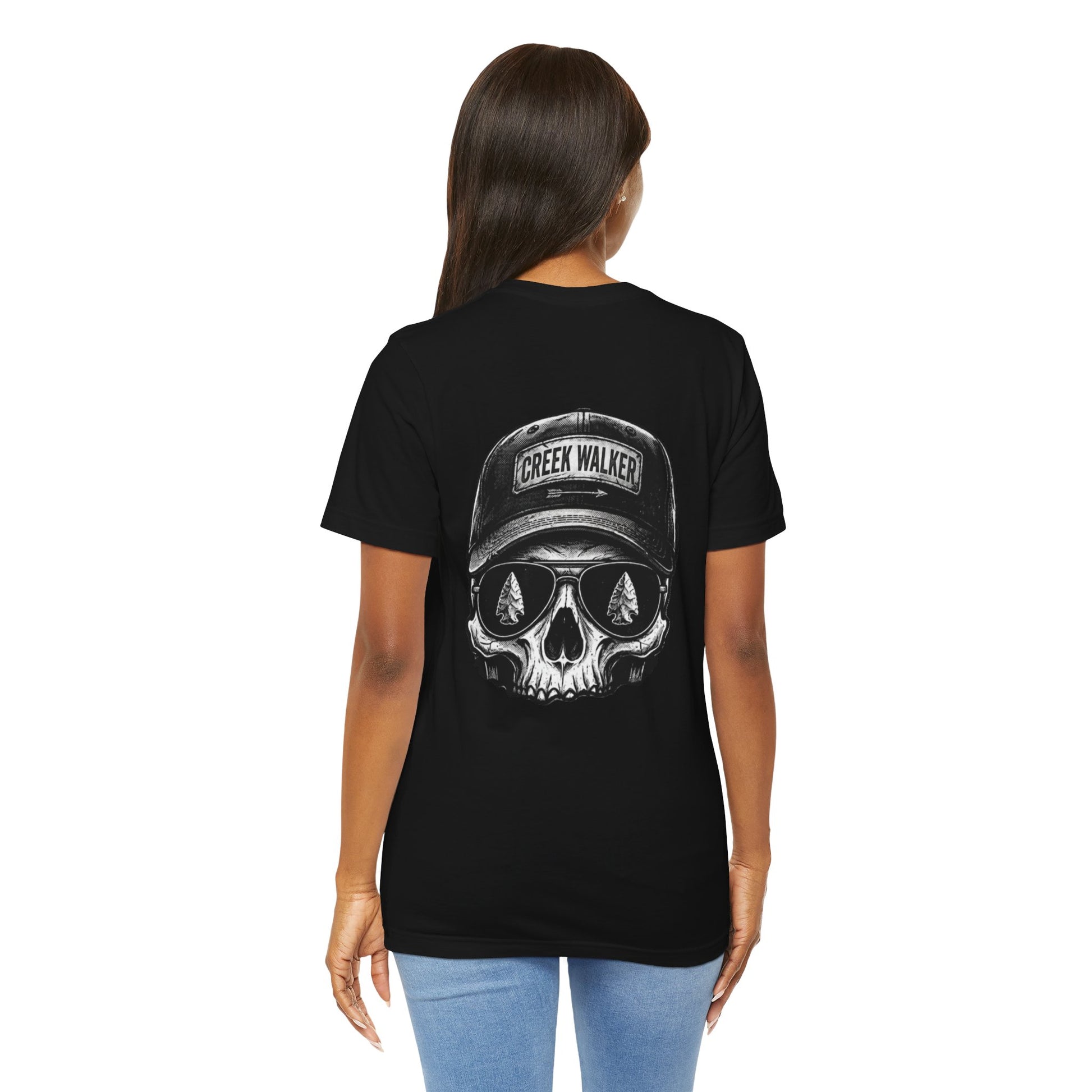 Distressed monochrome graphic on a black shirt showing a human skull wearing a baseball hat with "Creek Walker" written on it and aviator sunglasses that reflect ancient arrowheads.