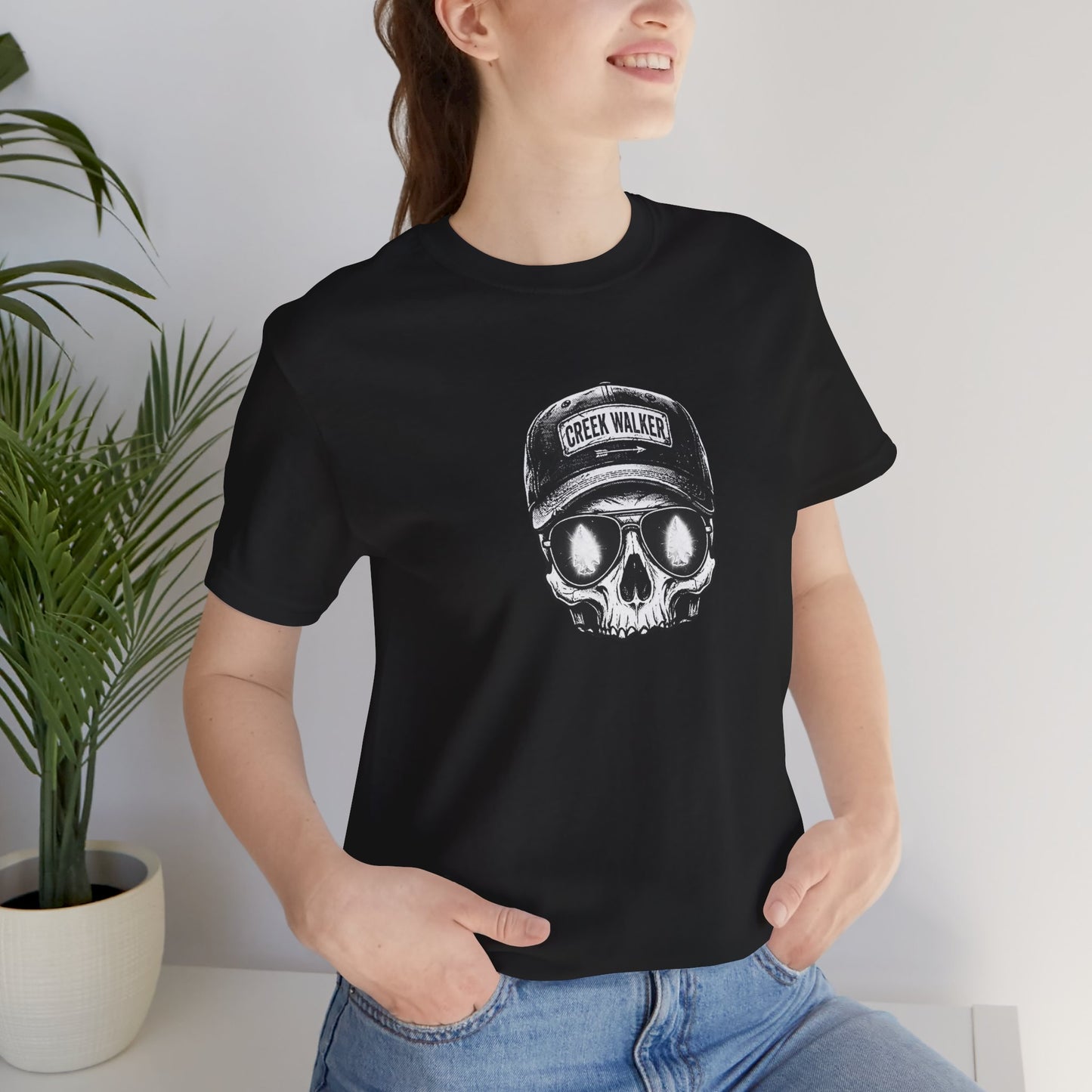 Distressed human skull graphic on a black shirt wearing a Creek Walker baseball cap and aviator sunglasses reflecting a glowing white arrowhead.