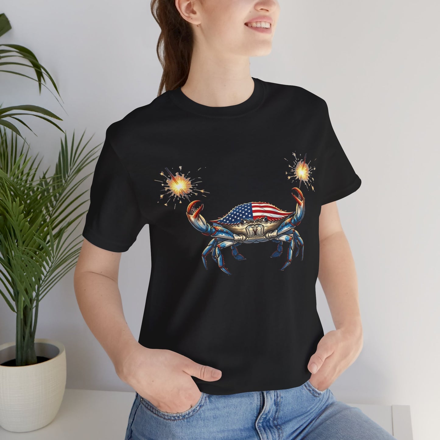 Graphic artwork of a detailed blue crab with an American flag pattern on its shell, holding two glowing, lit sparkler fireworks in its claws against a black background.